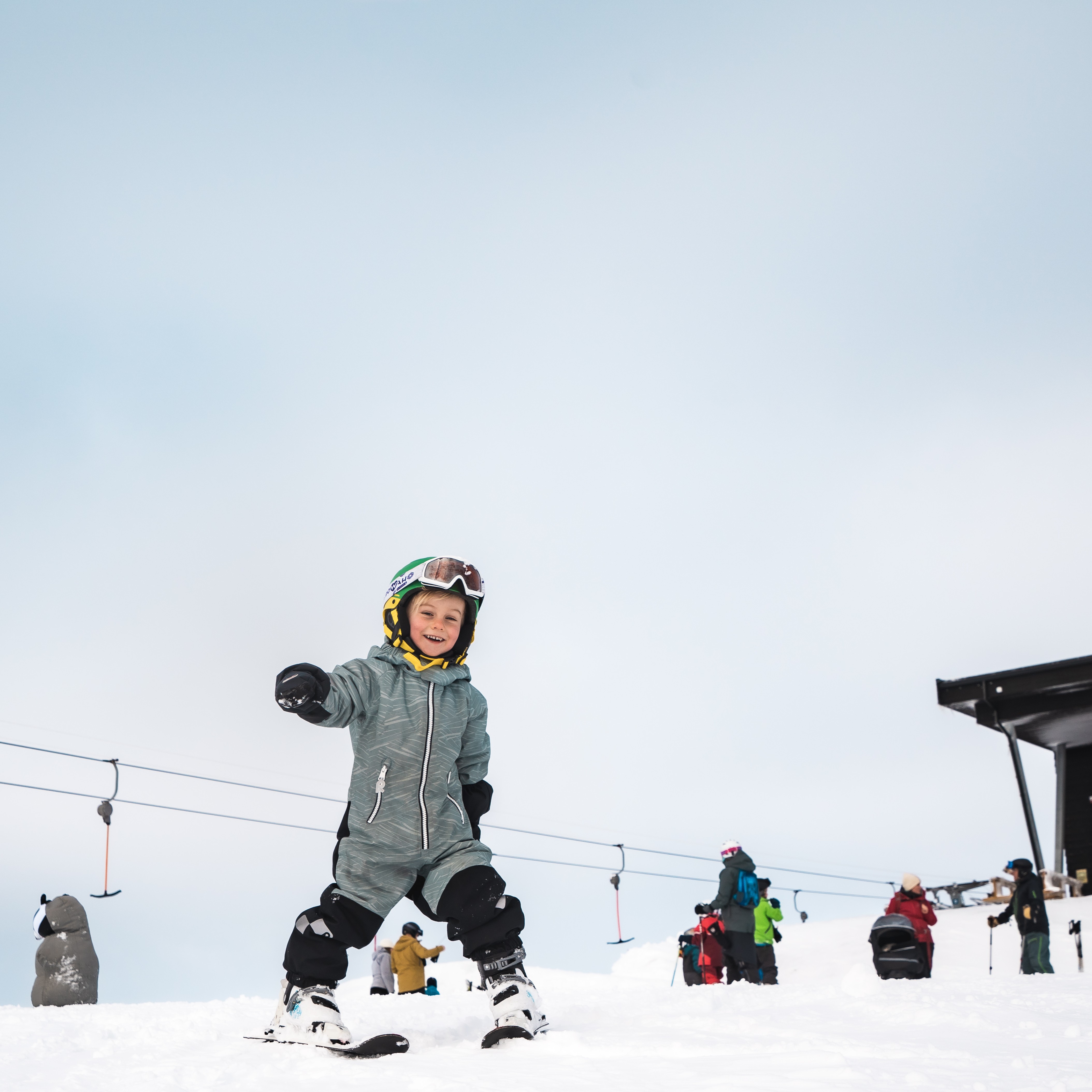 barn smiler og står på ski, ved hangurstoppen