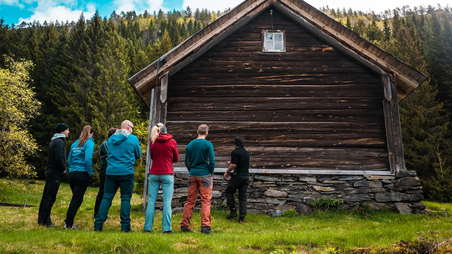 Ein gjeng studerer eit bygg på Hustveit gard