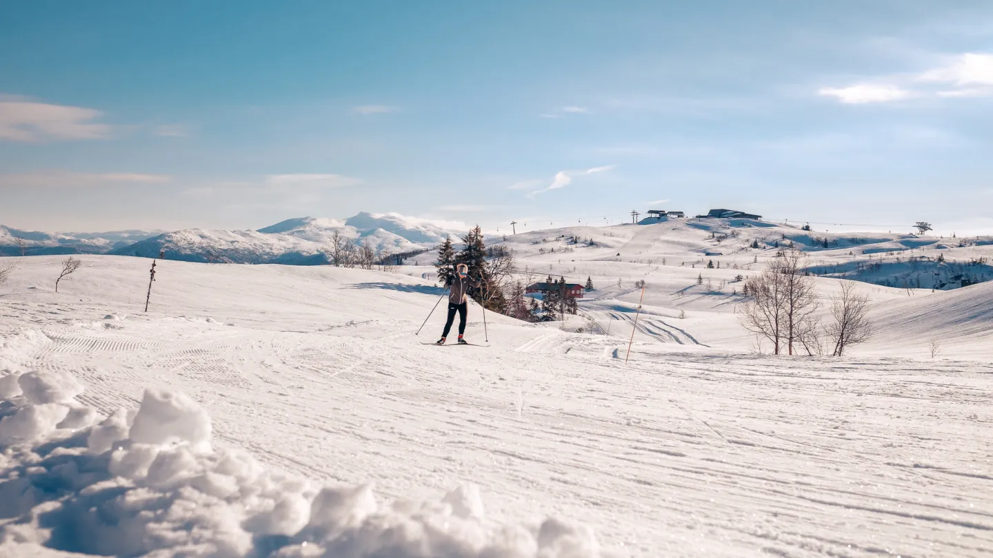 dame på langrenn i vinterlandskap, i bakgrunnen hangurstoppen restaurant